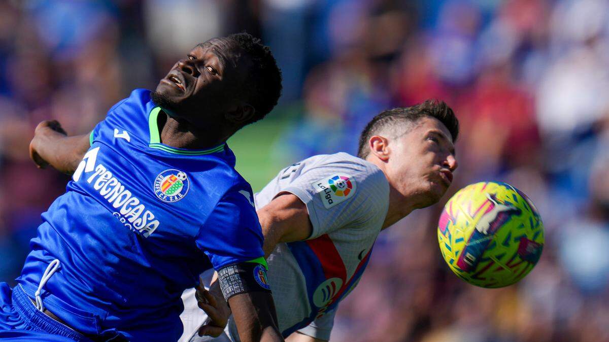 El jugador de Getafe Djene Dakonam (izq.) lucha por la pelota con Robert Lewandowski, de Barcelona, en el partido celebrado el 16 de abril de 2023 en Getafe, España.