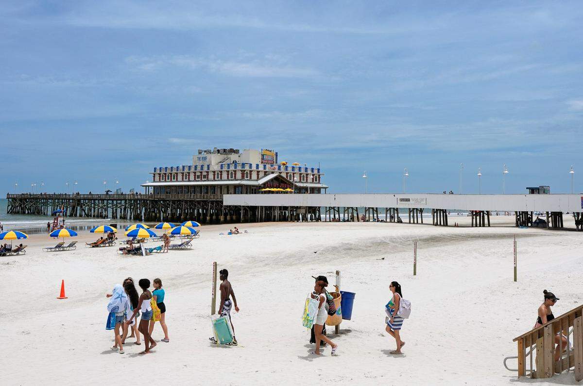 Los bañistas se dirigen al agua en Daytona Beach, el martes 8 de julio de 2025. Las políticas del presidente estadounidense Donald Trump, entre las que se incluyen sus medidas antimigración y aranceles generalizados, empiezan a hacer mella en el turismo.