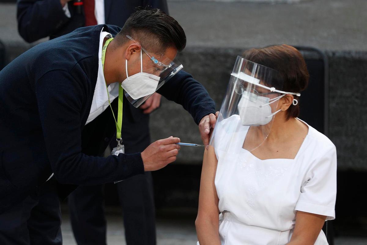 La trabajadora de salud María Ramírez es la primera en vacunarse contra el COVID-19 en el Hospital General de la Ciudad de México, el jueves 24 de diciembre de 2020 en la madrugada. Los primeros lotes de vacunas producidas por Pfizer y su socio alemán, BioNTech llegaron el día anterior.