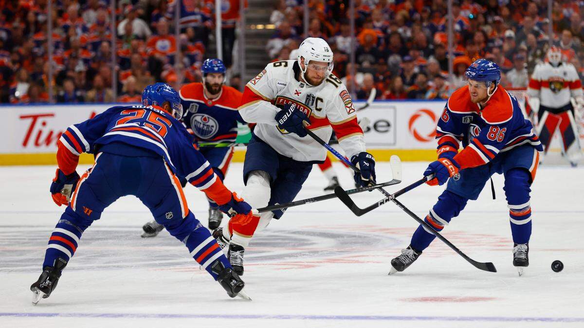 El jugador de los Panthers de Florida Aleksander Barkov (centro) trata de pasar la defensa de dos jugadores de los Oilers, en el tercer partido de la final de la NHL, celebrado el 13 de junio de 2024 en Edmonton, Canadá.