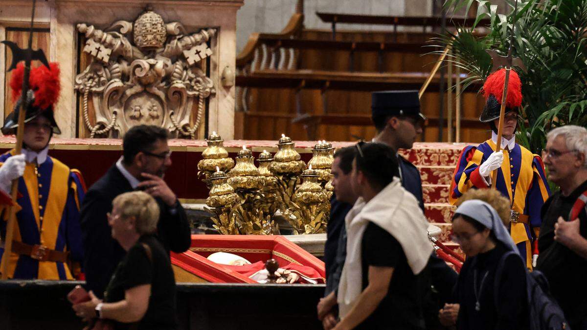 Varias personas caminan frente al féretro del papa Francisco, durante la capilla ardiente en la Basílica de San Pedro en el Vaticano, el miércoles, 23 de abril de 2025.