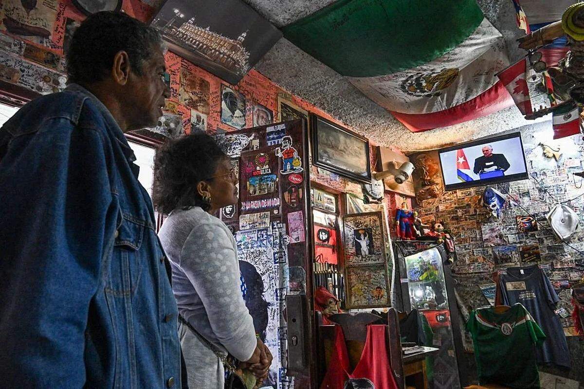 Dos personas miran al gobernante Miguel Díaz-Canel en la Televisión Nacional, en La Habana el jueves.