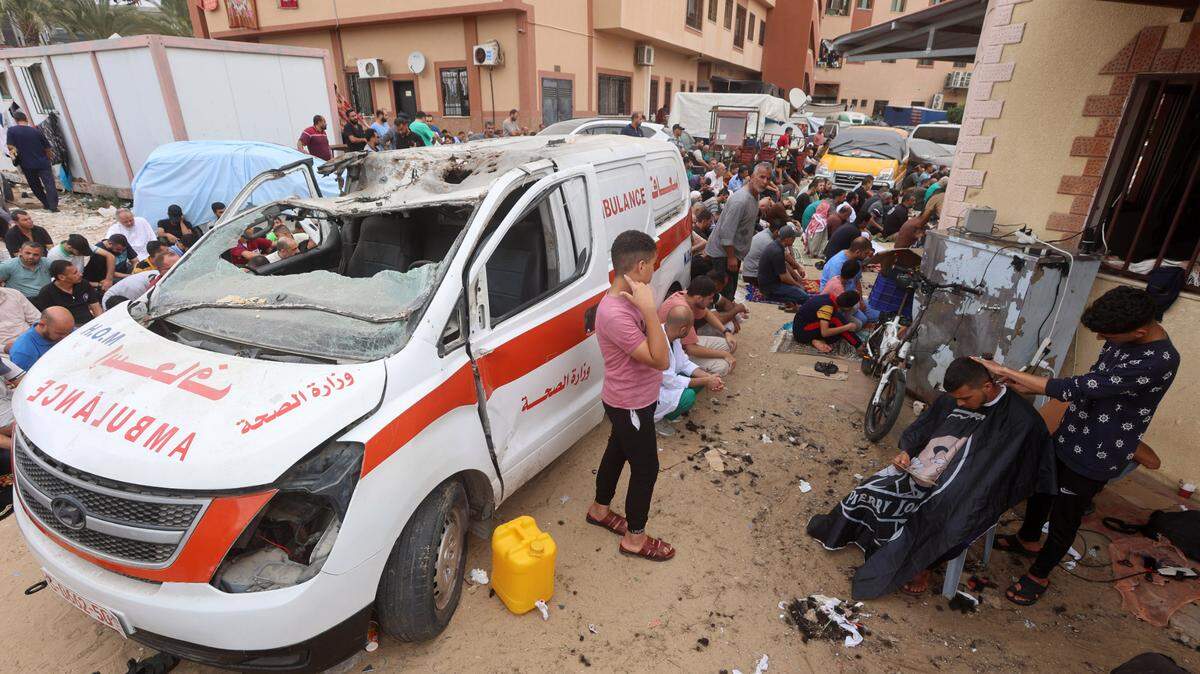 Palestinos rodean una ambulancia destruida por los bombardeos, durante una ronda de oraciones el viernes, 27 de octubre de 2023, en la entrada del hospital Nasser, en el sur de Gaza.