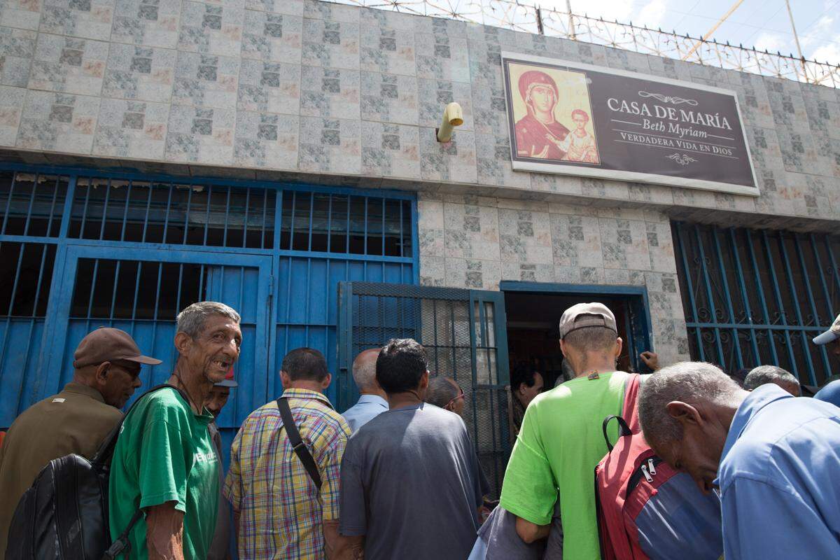 Numerosas personas hacen fila para comer sopa en la Casa de María a la hora del almuerzo en Propatria, Caracas. Para muchos es lo único que comen ese día.
