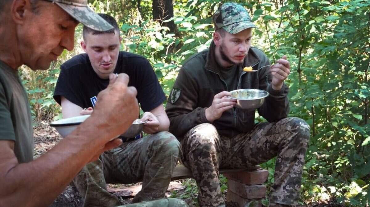 Soldados de la Defensa Territorial de Ucrania almuerzan en su puesto defensivo en el bosque el 29 de junio de 2022, en la región de Kramatorsk, Ucrania. Voluntarios de España y otros países están uniendo fuerzas con la población local en la ciudad occidental de Leópolis para preparar comidas deshidratadas destinadas a miles de soldados ucranianos en el frente.