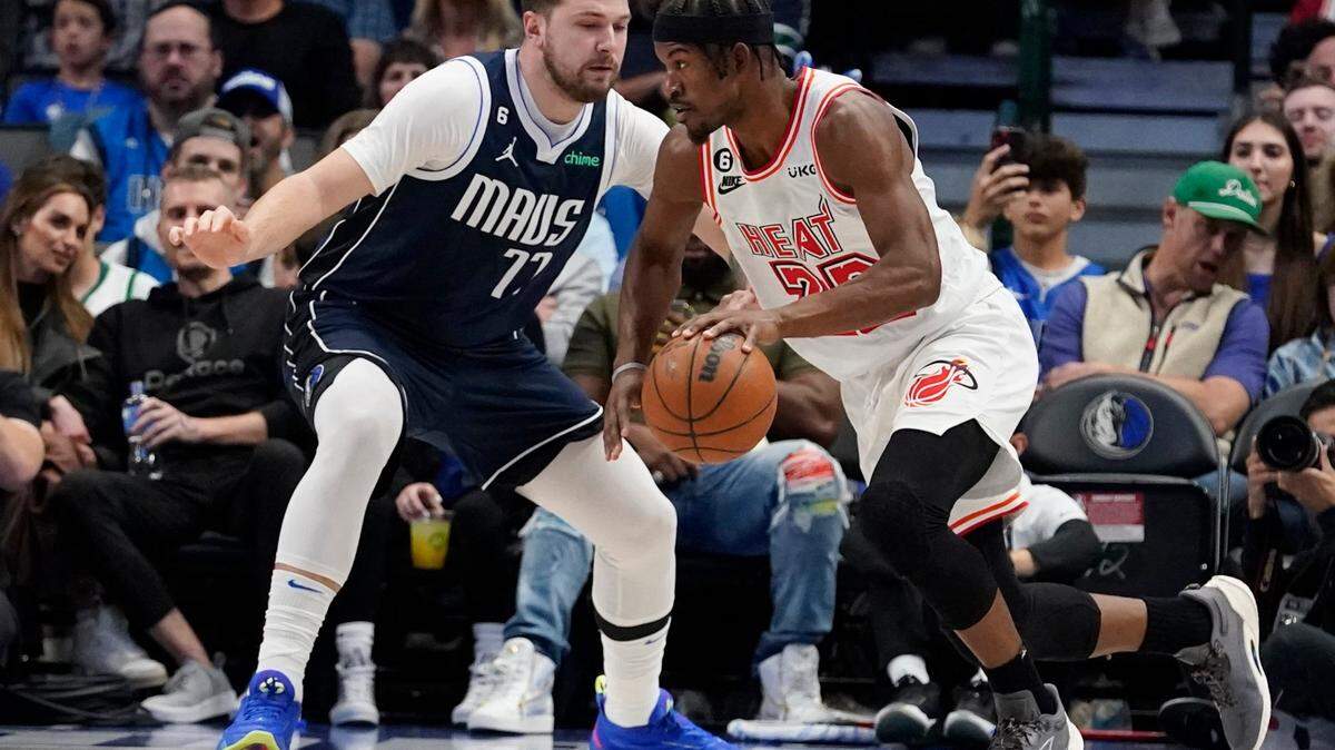 El delantero del Miami Heat, Jimmy Butler (22), conduce contra el escolta de los Dallas Mavericks, Luka Doncic (77), durante la primera mitad de un partido de baloncesto de la NBA en Dallas, el viernes 20 de enero de 2023.