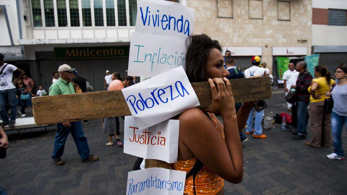 Una mujer protesta en Caracas con carteles en una cruz durante la Semana Santa del 2014.