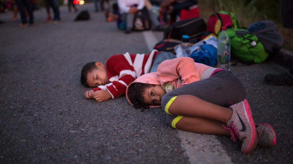 Los niños esperan a un lado del camino mientras una caravana de centroamericanos continúa su lenta marcha hacia la frontera de los EEUU, Cerca de Tapanatepec, México.