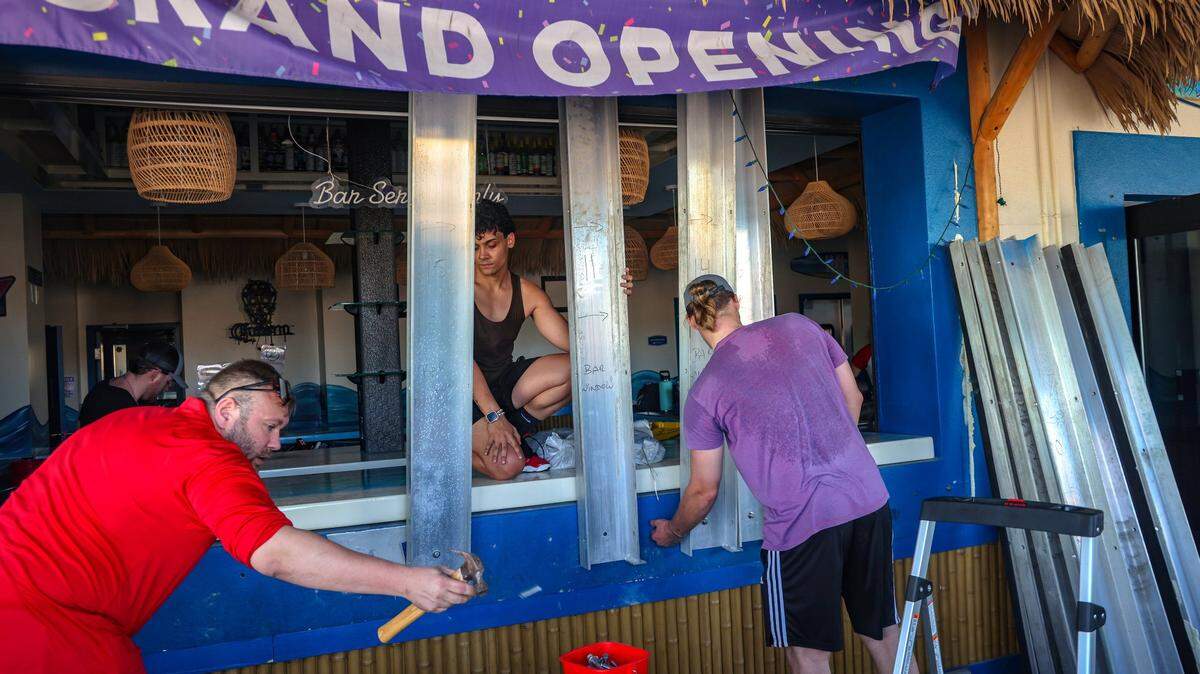 Orlando Vega, 26, center, and Christopher Boyce Jr, 25, right, assist Daniel Clarkston, 36, center, in removing metal shutters at Mr. Waves Island, a bar and grill, as business owners and residents begin the cleanup process after Hurricane Milton on Thursday, October 10, 2024, at Fort Myers Beach. Two years after Hurricane Ian devastated the small barrier island of Fort Myers Beach, killing 14 people and leaving almost every home and business in ruins, the lives of residents and shopkeepers who heeded warnings to get out as another powerful storm approached were spared.