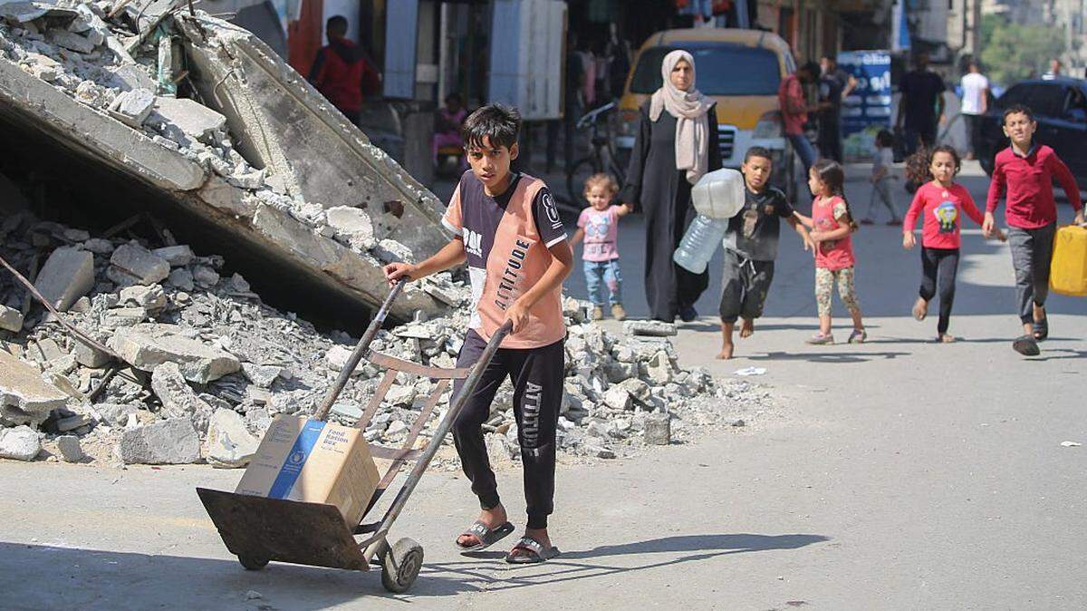 A dispilaced Palestinian boy wheels a box of emergency supplies provided by the World Food Programme (WFP) after receiving it from an aid distribution point at the Nuseirat refugee camp in the central Gaza Strip, on October 19, 2025. Israeli Prime Minister Benjamin Netanyahu has warned the war in Gaza will not be over until Hamas disarms and the Palestinian territory is demilitarised while relief agencies continue to call for the Rafah border crossing from Egypt to be reopened to speed the flow of food, fuel and medicines. (Photo by Eyad BABA / AFP) (Photo by EYAD BABA/AFP via Getty Images)