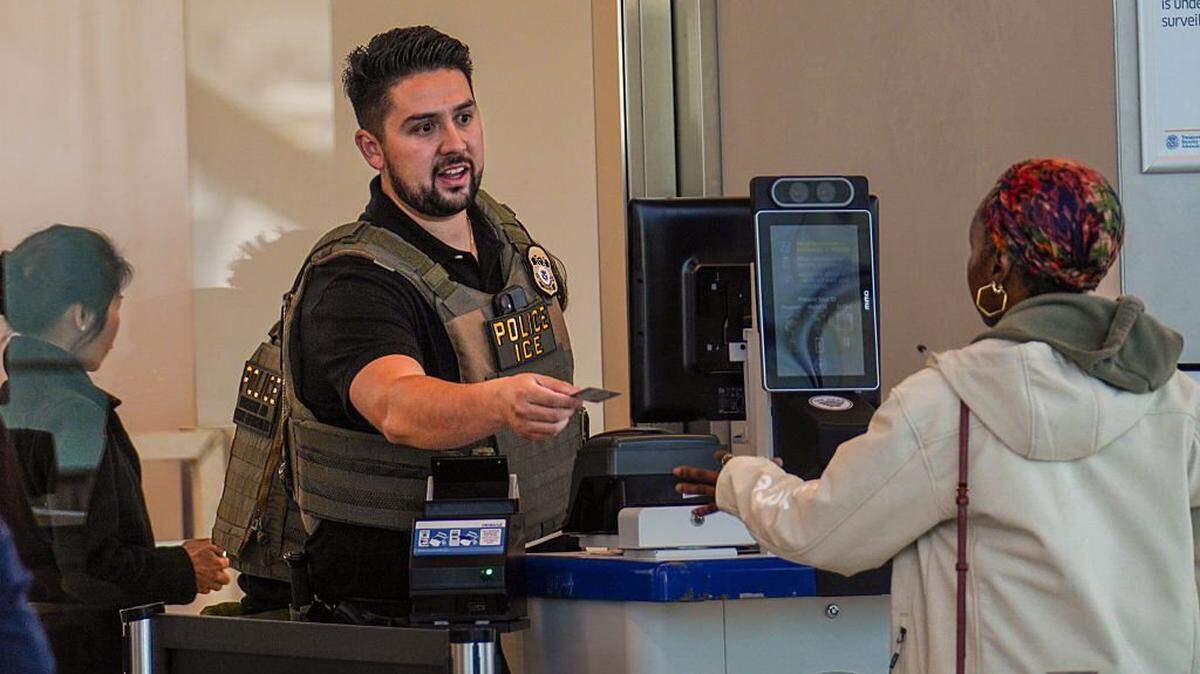 Un agente del ICE entrega su identificación a un viajero en un puesto de control de seguridad de la TSA en el Aeropuerto LaGuardia, el 28 de marzo de 2026, en Nueva York, Nueva York. Las interrupciones en los viajes continúan mientras cientos de agentes de la TSA renuncian o trabajan sin remuneración durante un cierre parcial del gobierno.