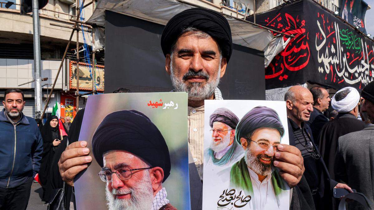 Un clérigo musulmán chiita posa con fotografías del nuevo líder supremo de Irán, el ayatolá Mojtaba Jamenei (derecha), y su difunto padre Ali Jamenei (izquierda), durante una manifestación en su apoyo en la Plaza Enghelab, en el centro de Teherán, el 9 de marzo de 2026.
