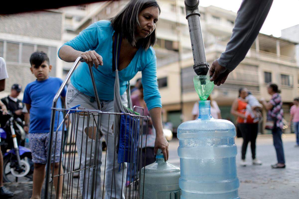 Una mujer llena un envase con agua en un barrio de Caracas el 27 de marzo del 2019 durante el nuevo apagón que ha incrementado el descontento en la población.