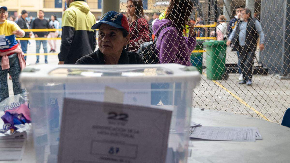 Un trabajador electoral se sienta junto a una urna con votos en la Escuela Arturo Alessandri Palma durante las Elecciones Primarias de Venezuela. Santiago, Chile. 22 de octubre de 2023. 