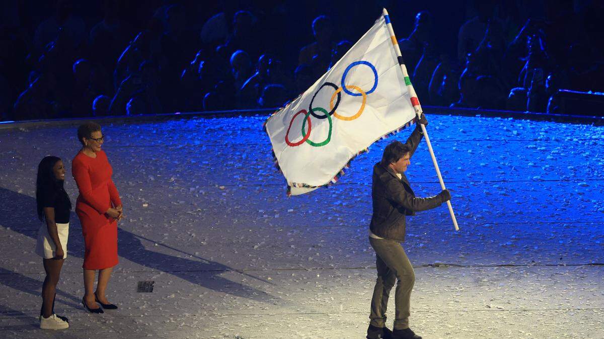 El actor Tom Cruise muestra la bandera de los Juegos Olímpicos junto a la gimnasta Simone Biles y la alcaldesa de Los Ángeles, Karen Bass, en representación de la ciudad californiana que será la sede de la competencia en 2028, durante la ceremonia de clausura el domingo en París.