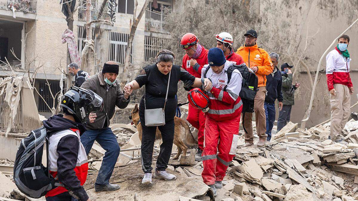 Una mujer es ayudada a abrirse paso entre los escombros por los equipos de rescate tras un ataque a un edificio residencial el lunes, 16 de marzo de 2026, en el centro de Teherán, Irán.