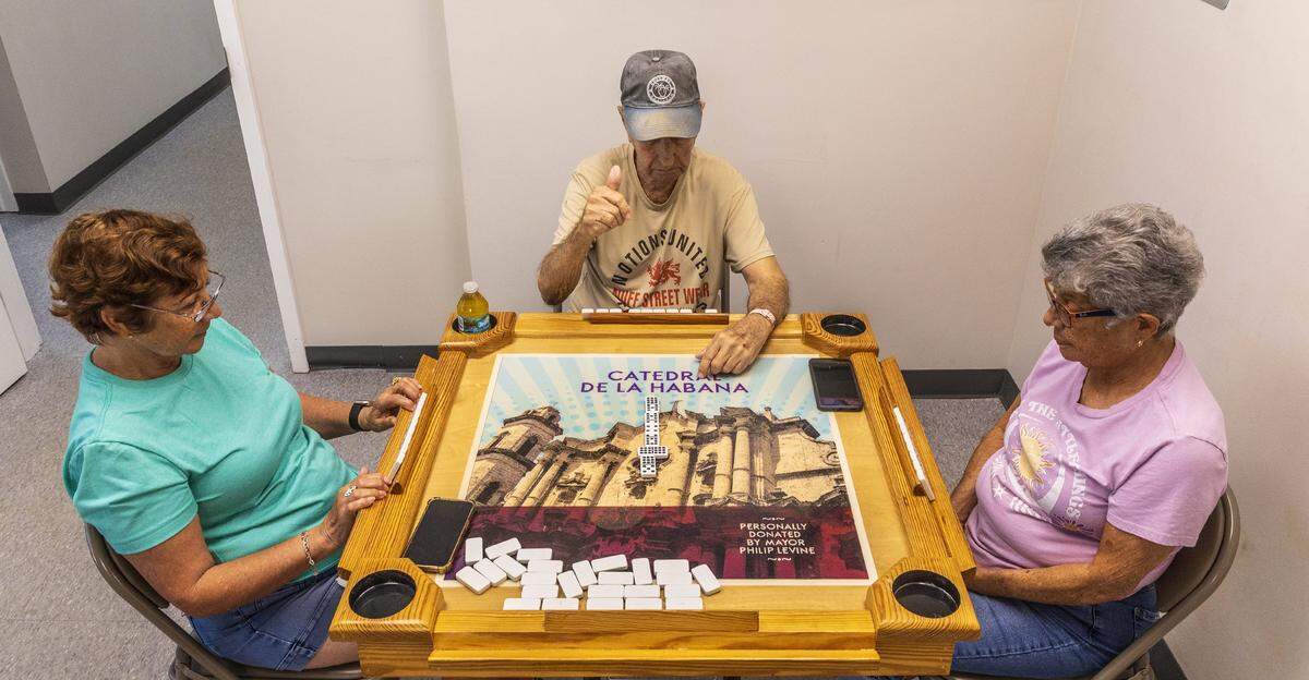 De izquierda a derecha: Blanca Rebelled, Jorge Garrido y María Esther Salgado juegan dominó en el Centro Familiar Diener de Miami Beach, donde los miembros reciben almuerzo, clases de fitness y entretenimiento gratuitos durante todo el año. Servicios Comunitarios Judíos, la organización sin fines de lucro propietaria del centro, es una de las más de 50 organizaciones sin fines de lucro que están perdiendo fondos importantes debido a los recortes presupuestarios del condado de Miami-Dade.