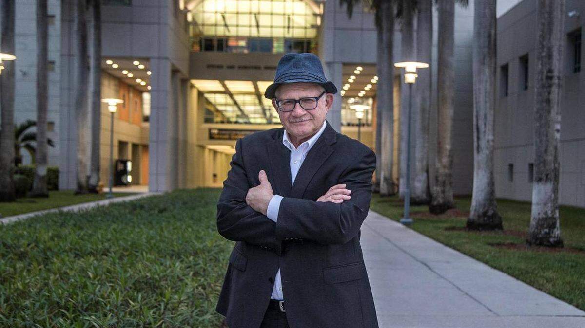 Mark Rosenberg, who resigned as president of Florida International University in January 2022, stands in front of the Steven and Dorothea Green Library at FIU’s Modesto Maidique campus in southwest Miami-Dade on Dec. 14, 2021. He will return in January to teach one class per semester.