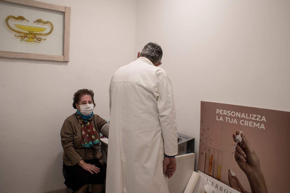 Alessio Berti, un farmacéutico local, le toma la presión arterial a un paciente en Castellina, Italia.