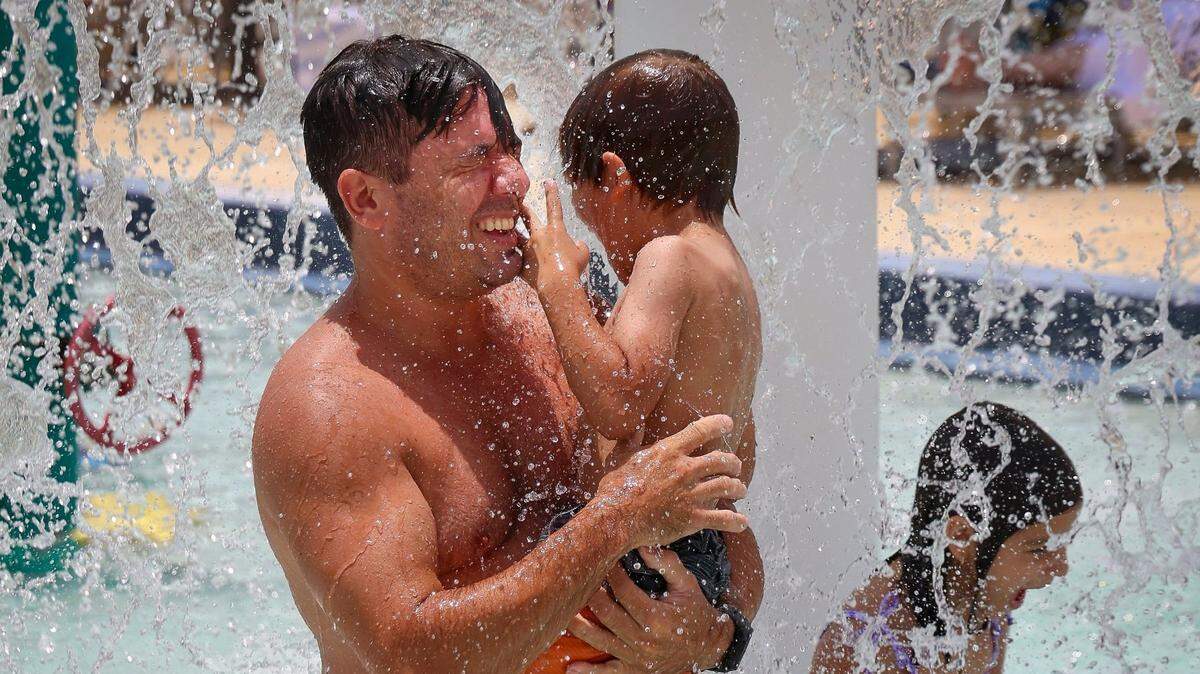 Foto de archivo del 16 de julio de 2023 que muestra a Erwin Schmitz (izq.), un residente de North Bay Village, y a su hijo, Liam, tratando de refrescarse en la piscina para niños del Parque Normandy Isle, cerca de Miami Beach. 