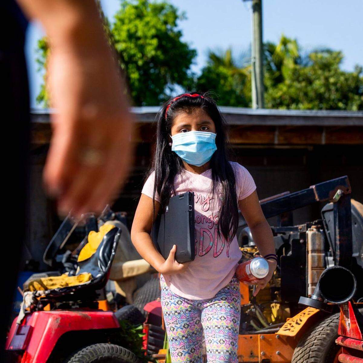 Una pequeña niña emigrante camina al encuentro de una empleada de las escuelas de Miami-Dade que ayuda a los niños en estudios virtuales durante la pandemia del coronavirus.
