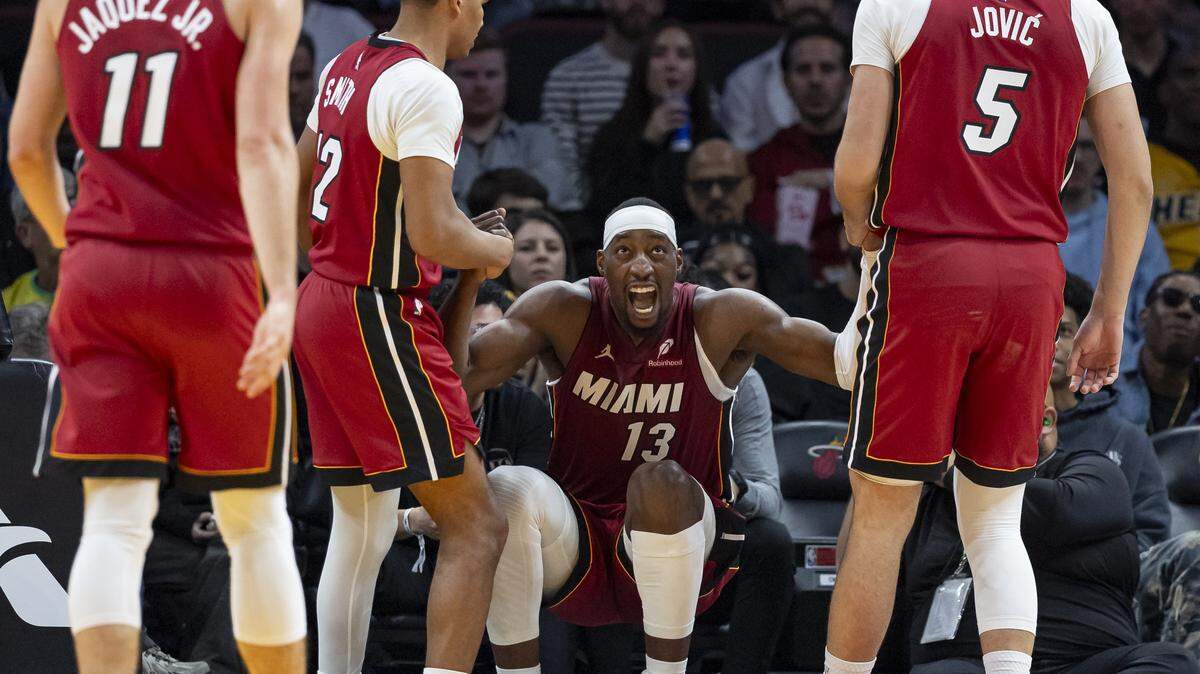 El armador del Heat, Dru Smith (12), y el delantero Nikola Jovic (5) ayudan al pívot Bam Adebayo (13) a levantarse tras una jugada contra los Chicago Bulls en la primera mitad de su partido de la NBA en el Kaseya Center el sábado 31 de enero de 2026, en el centro de Miami, Florida.
