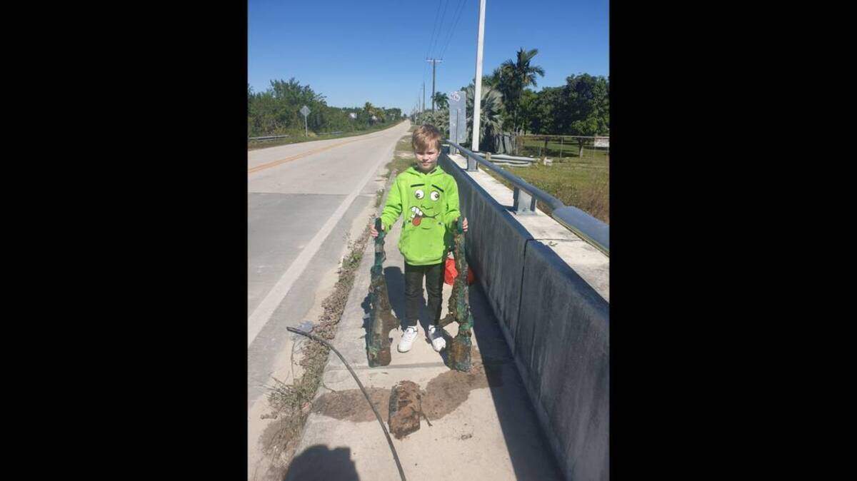 Allen Cadwalader, de 11 años, sostiene los dos fusiles Barrett con mira telecópica de calibre .50, que él y su abuelo hallaron en un canal de Miami-Dade, el 30 de enero de 2022.