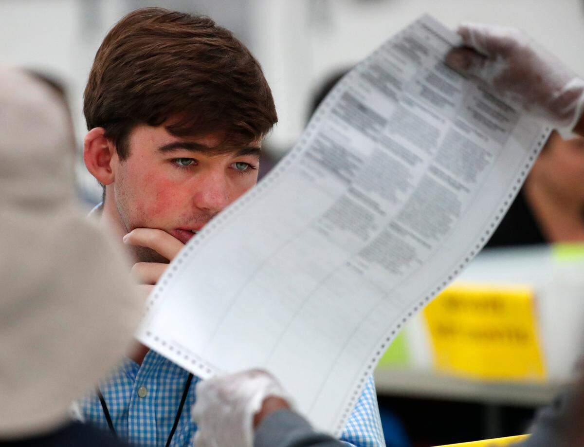 Un observador republicano observa una boleta durante el recuento manual en la oficina de la Supervisora de Elecciones de Broward en Lauderhill, Florida, en una imagen del viernes 16 de noviembre del 2018.