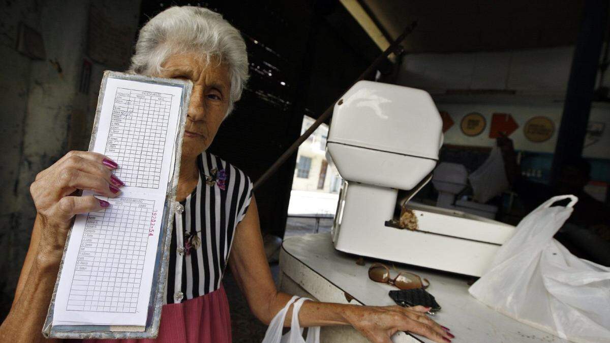 Una anciana muestra su libreta de racionamiento en una bodega de La Habana (Cuba)