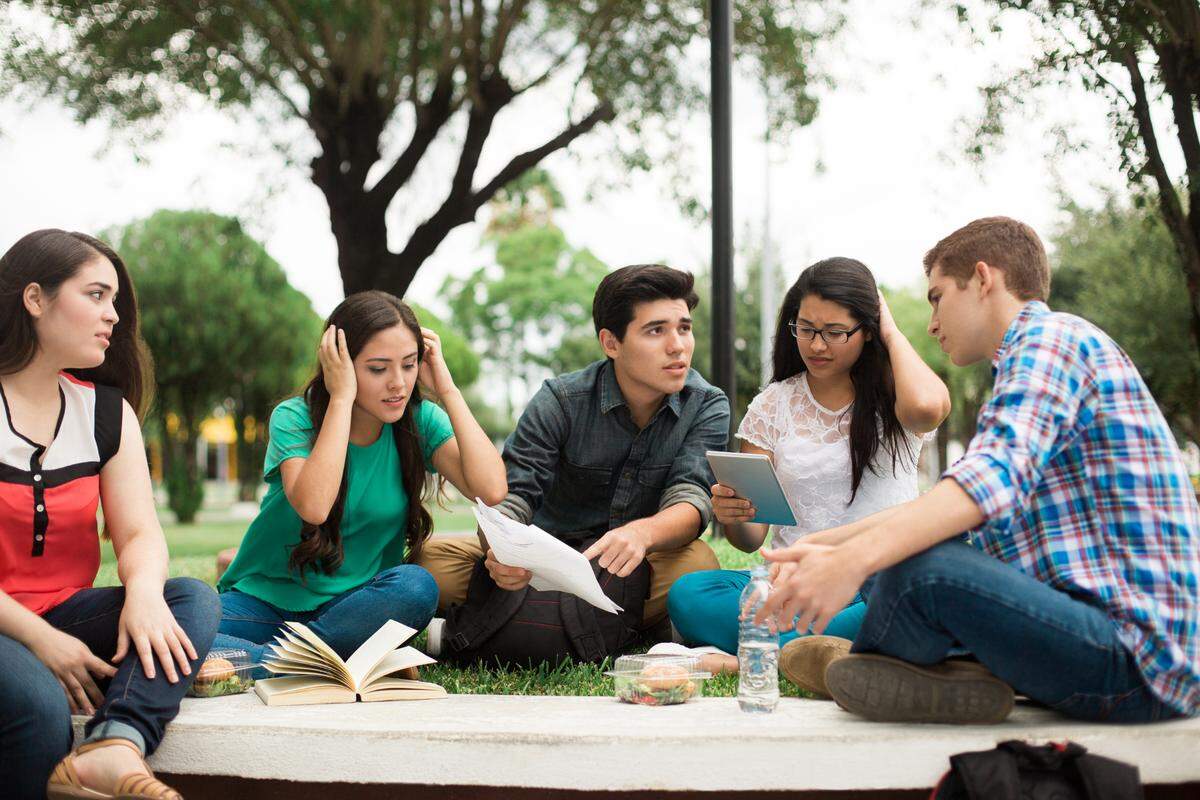 A small group of worried students studies outdoors.