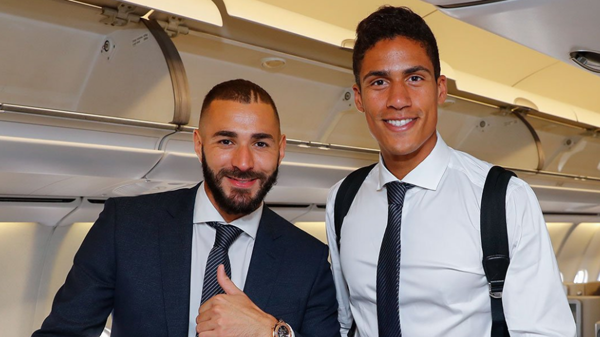 Karim Benzema (izq.) y Raphael Varane posan en el avión que transportó a los jugadores del Real Madrid a la ciudad de Tallín, Estonia, sede del partido por el título de la Supercopa de Europa que disputarán el miércoles ante el Atlético de Madrid.