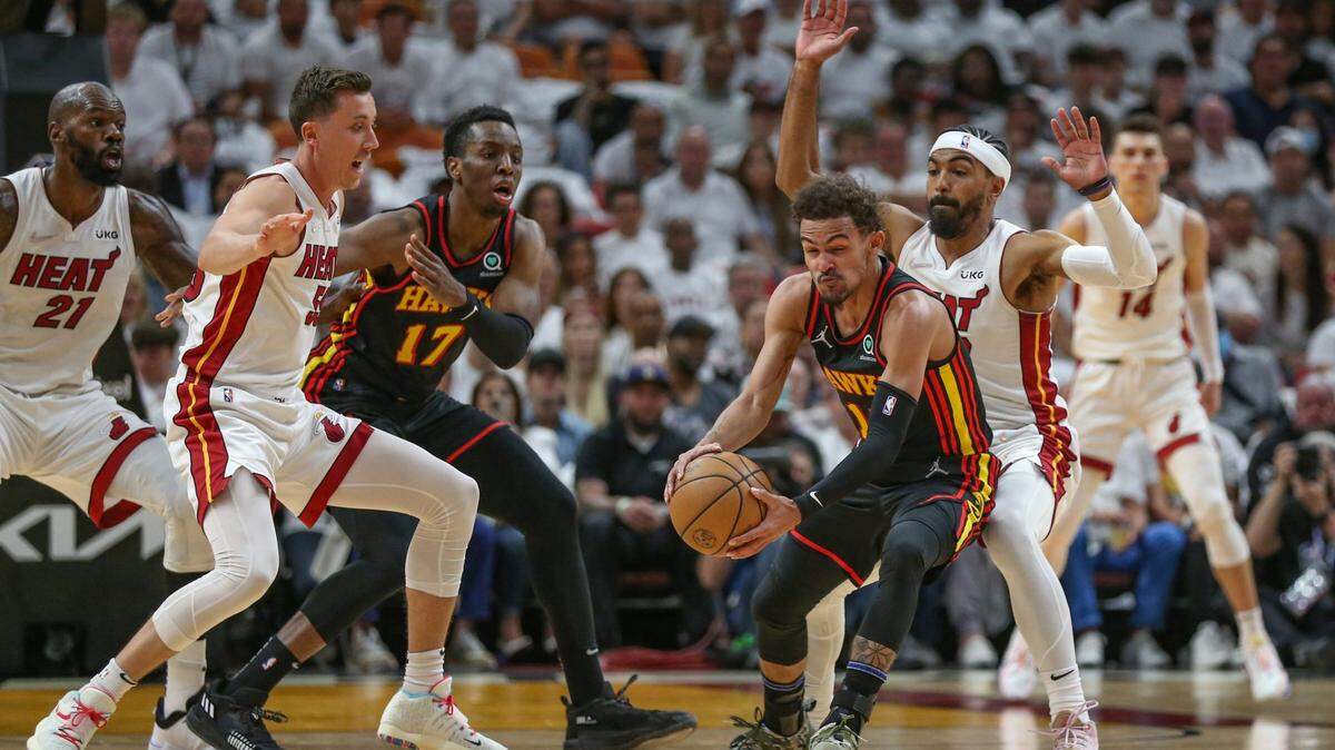 La estrella de los Hawks de Atlanta Trae Young (centro) trata de pasar la marca de Duncan Robinson (55) y Gabe Vincent, en el segundo partido de la serie de playoffs celebrado el 19 de abril de 2022 en Miami.