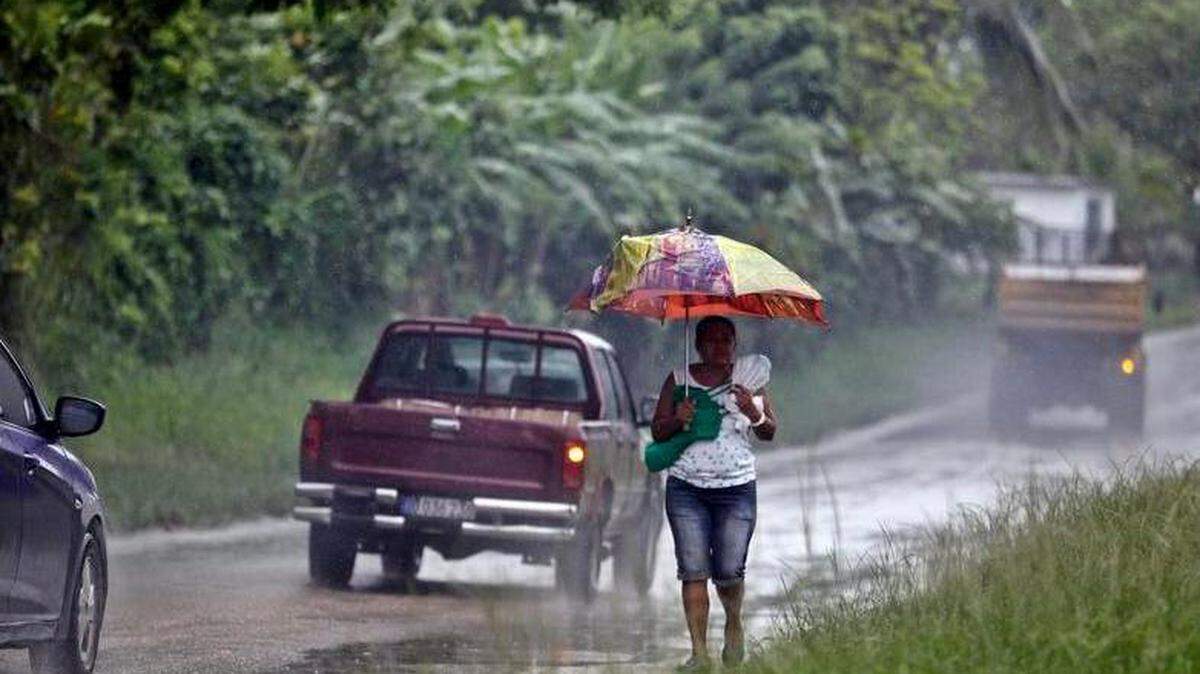 Una mujer camina por la orilla de una carretera durante un fuerte aguacero hoy, martes 29 de mayo del 2018, en La Habana (Cuba).