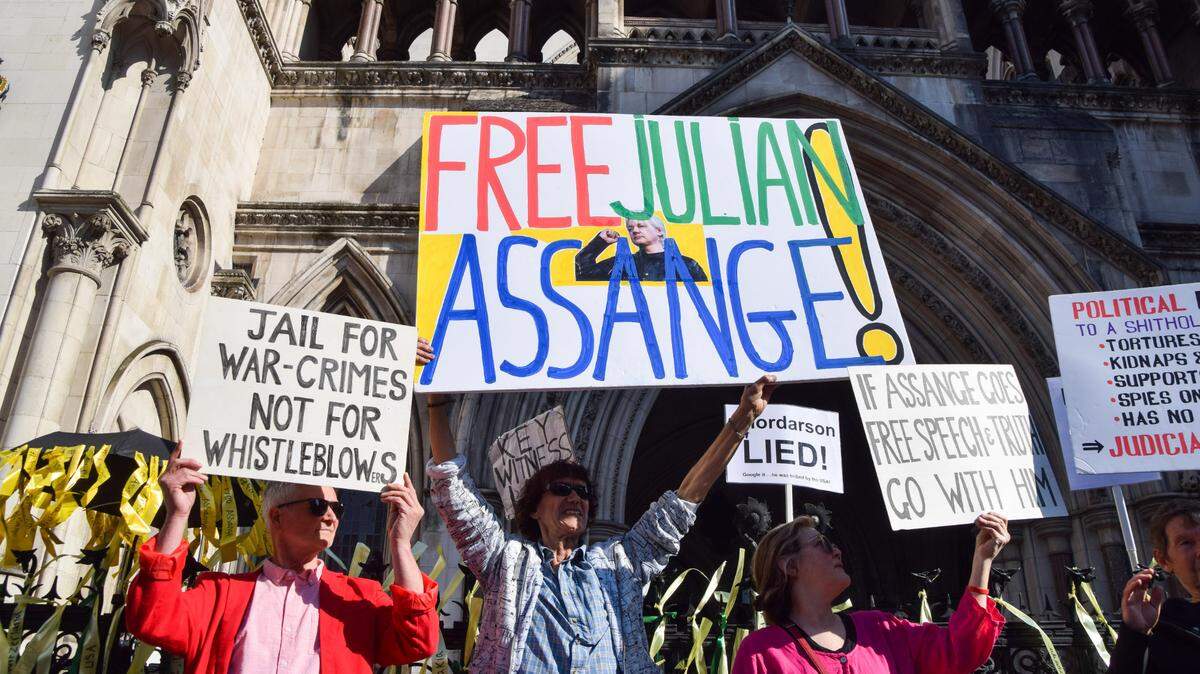 Un grupo de personas sostienen pancartas en apoyo de Julian Assange durante una manifestación frente al Tribunal Superior de Londres, el 20 de mayo de 2024.
