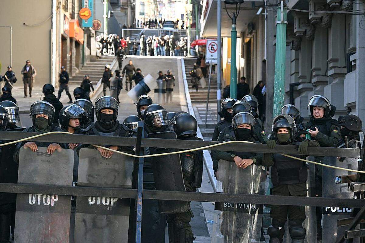 Agentes de la policía antidisturbios montan guardia mientras estallan enfrentamientos con mineros durante una marcha para exigir la renuncia del presidente boliviano, Rodrigo Paz, en La Paz, el 14 de mayo de 2026.