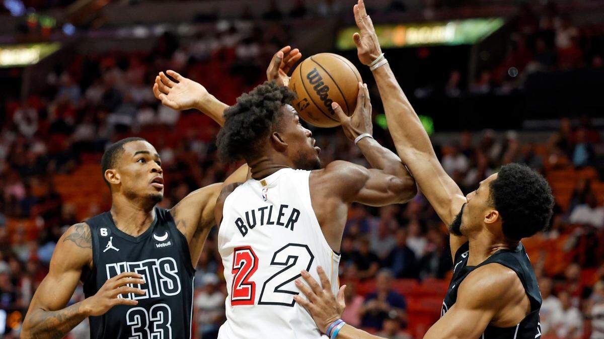 El alero del Miami Heat Jimmy Butler (22) intenta una canasta mientras el centro de los Brooklyn Nets, Nic Claxton (33) y el guardia Spencer Dinwiddie (26) en el primer cuarto en el Miami-Dade Arena en Miami, Florida. el sábado 25 de marzo de 2023.