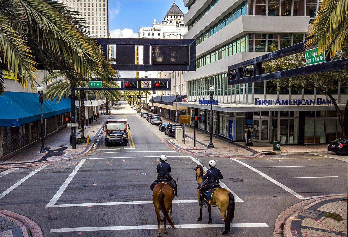 Los agentes de la Patrulla Montada de la Ciudad de Miami, Loisel Cruz montando a Ike, a la izquierda, y Rubén González montando a Cody, a la derecha, patrullan a lo largo de una calle tranquila y casi cerrada de Flagler en el centro de Miami debido a la amenaza de COVID-19 el miércoles 1 de abril de 2020 .