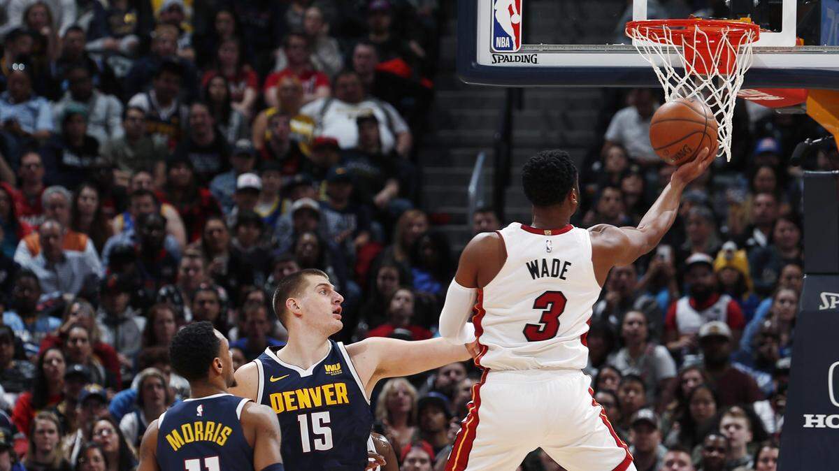 El escolta del Heat Dwyane Wade entra al aro ante la marca de Nikola Jokic (#15) y Monte Morris, de los Nuggets, en el segundo cuarto del partido celebrado el 11 de febrero de 2019 en Denver.