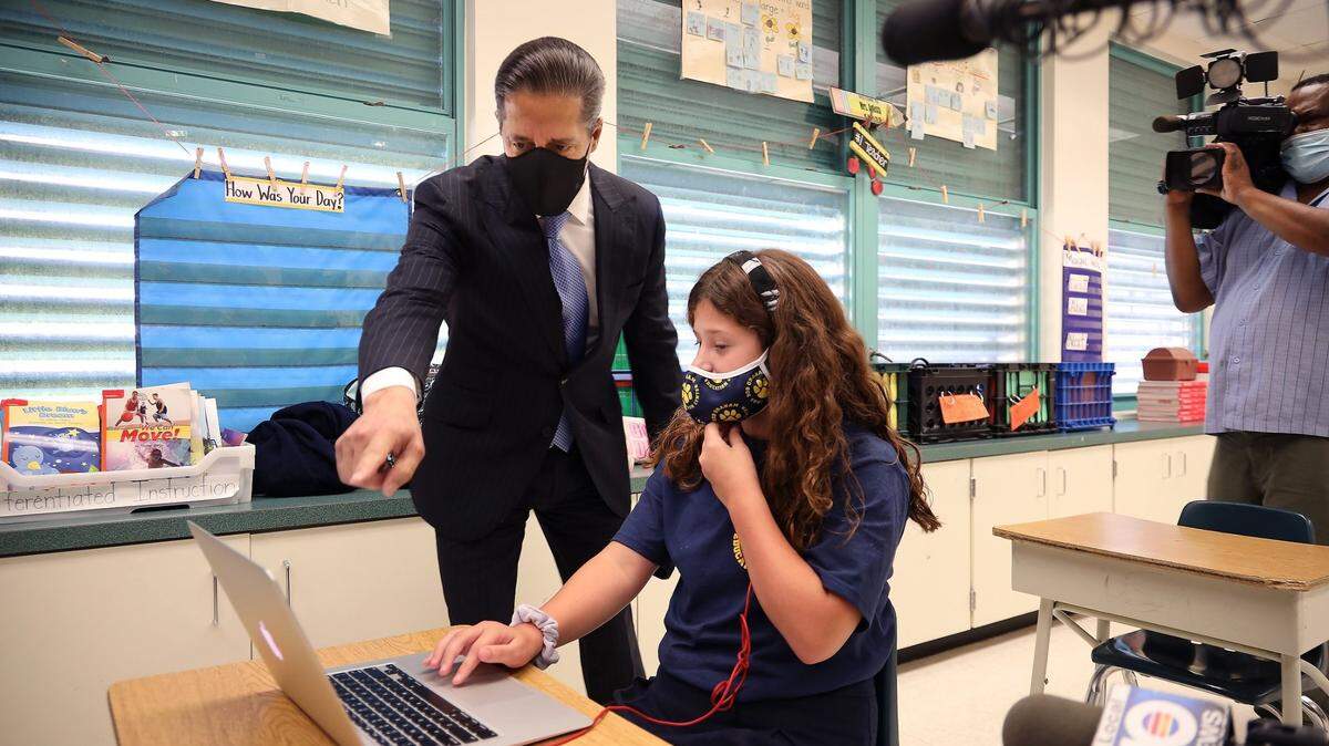 El superintendente Alberto M. Carvalho interactúa con la estudiante Emily Acosta, quien estaba tomando su clase de forma virtual en el salón en donde enseña su madre, durante el primer día de clases en el Centro Educativo Bob Graham, el lunes 31 de agosto de 2020.