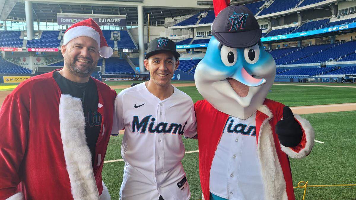 Gaby Sánchez, Jon Jay y Billy the Marlin en una entrega de juguetes por Navidad en el parque de la Pequeña Habana.