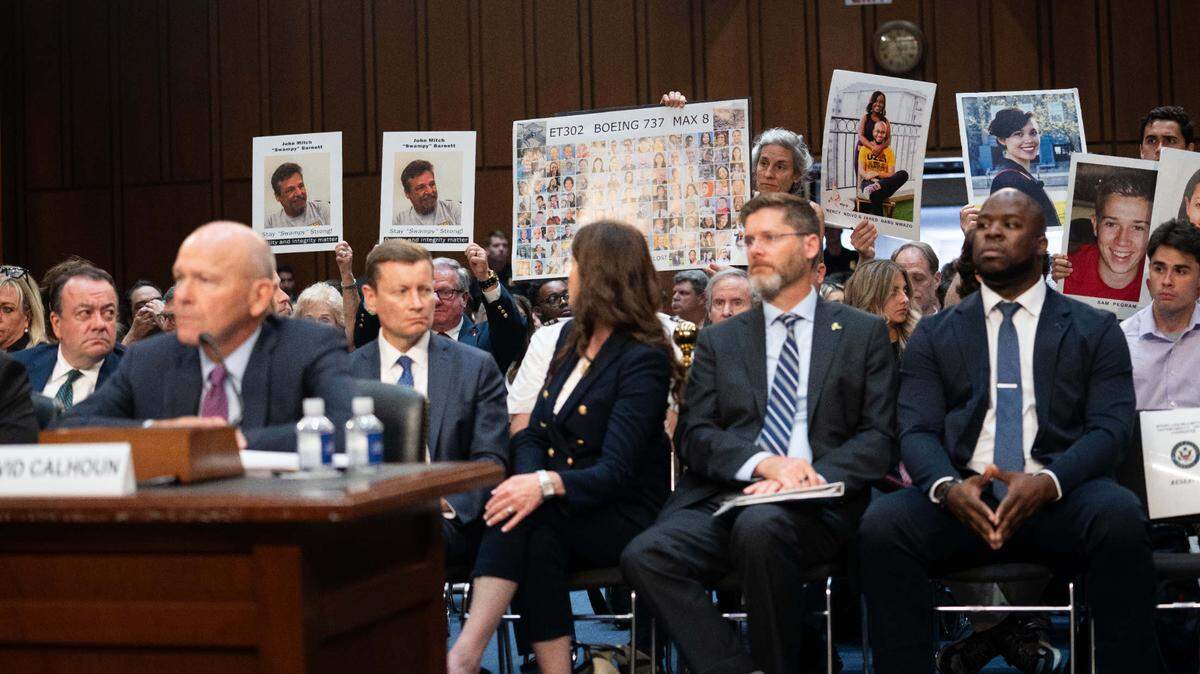 Familiares de víctimas de accidentes de Boeing exhiben sus fotos mientras el presidente y director ejecutivo del fabricante de aviones, Dave Calhoun (izq.), testifica durante una audiencia del subcomité de Asuntos Gubernamentales y Seguridad Nacional del Senado de Estados Unidos, el 18 de junio de 2024 en Washington DC.