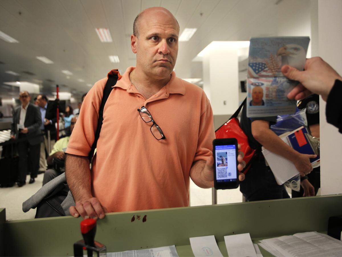 International traveler Louis Nicastro shows his Mobile Passport profile to an U.S. Custom agent during the last process to entry into the United States. Miami International Airport is embracing tech to help travelers have a better experience with use of their new Mobile Passport app, which lets people submit customs forms via their phone instead of on paper and then lets them use an expedited line. (Carl Juste/Miami Herald/TNS)