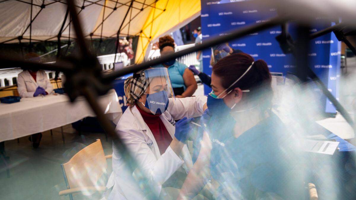 Mary Ezzat inocula a su colega del sector salud, Angela Serrano, con la vacuna de Pfizer-BioNTech contra el COVID-19 en unas instalaciones provisionales del Centro Médico Irvine de la Universidad de California.
