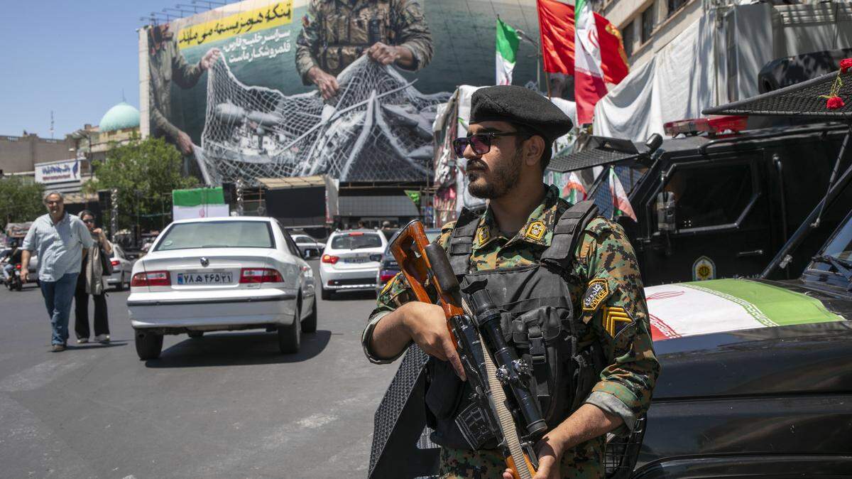 Un agente de policía iraní realiza una patrulla cerca de un cartel que muestra a soldados iraníes sosteniendo una red con forma del estrecho de Ormuz, con aeronaves militares estadounidenses atrapadas en una red de pesca, el 9 de mayo de 2026 en Teherán, Irán.