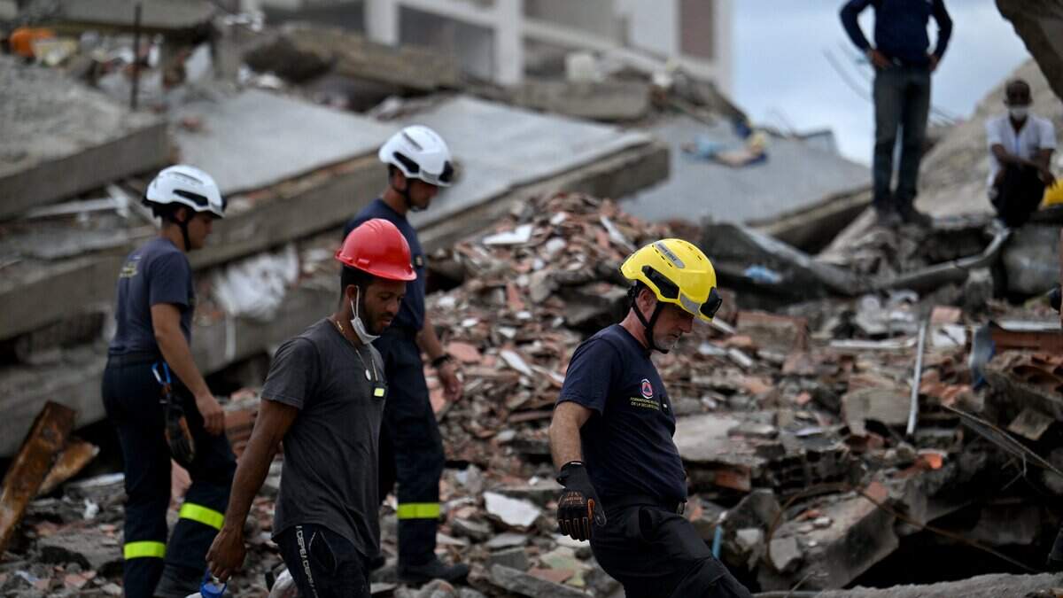 Members of a French Civil Security (Sécurité Civile) rescue team walk across the rubble of collapsed buildings in Caraballeda, La Guaira, Venezuela, on July 3, 2026. The death toll from Venezuela's twin earthquakes has risen to 2,595, Interim President Delcy Rodriguez said on July 2. (Photo by Juan BARRETO / AFP via Getty Images)