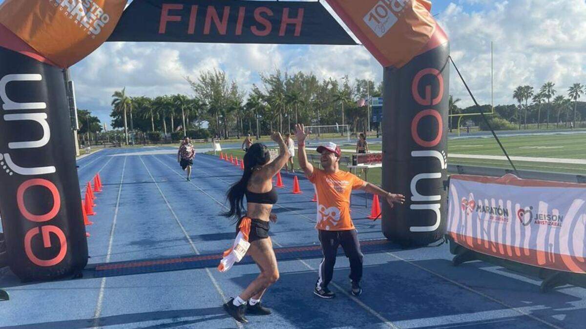 Jeison Aristizabal recibe en la meta a uno de los participantes en el Maratón de Sueños, el domingo 21 de agosto de 2022 en el Tropical Park en Miami.