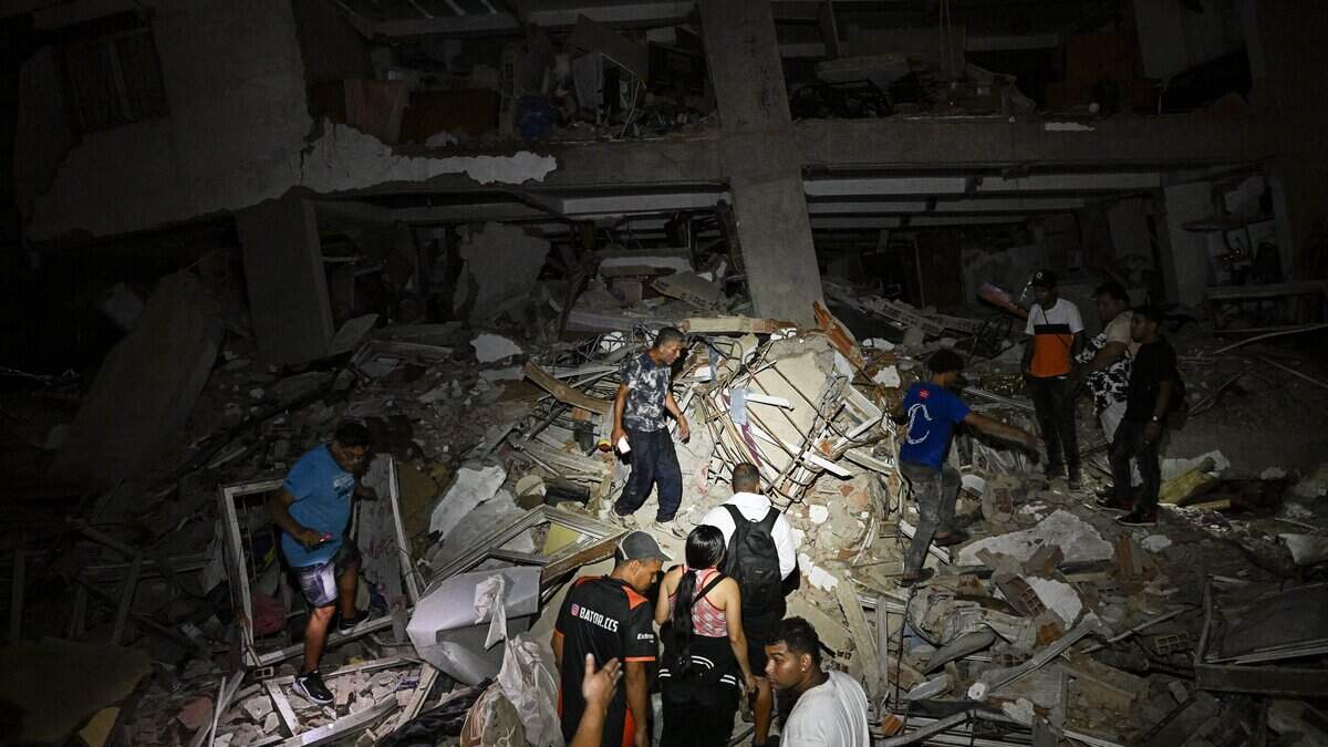 TOPSHOT - People walk in the rubble near a damaged building following an earthquake in Catia La Mar, La Guaira State, some 30kms north-west of Caracas, early on June 25, 2026. Powerful twin earthquakes have killed 32 people and injured more than 700, the nation's interim president said on June 25, after the massive shocks collapsed entire buildings and sent people running in panic. (Photo by Federico PARRA / AFP via Getty Images)