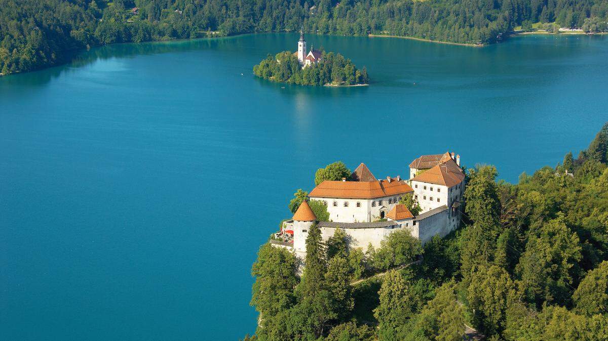 Una vista del castillo de Bled, en primer término, con el islote en el centro del lago al fondo.