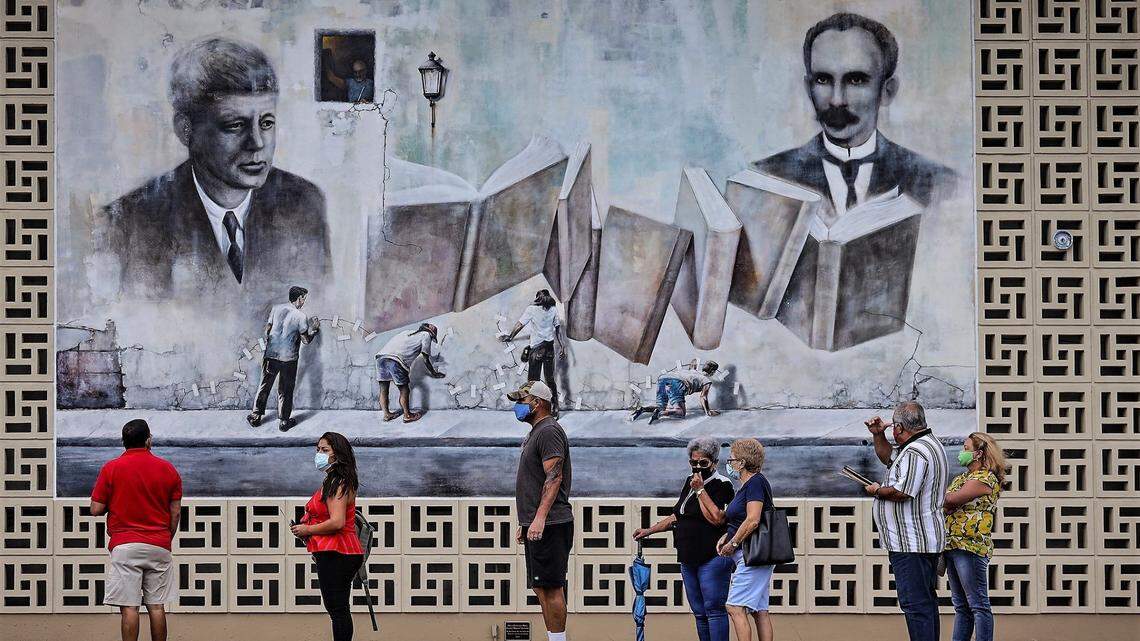 Steady flow of voters stand in line in front of the large mural outside the JFK Library in Hialeah, as Florida began its first day of early voting on Monday, October 19, 2020.