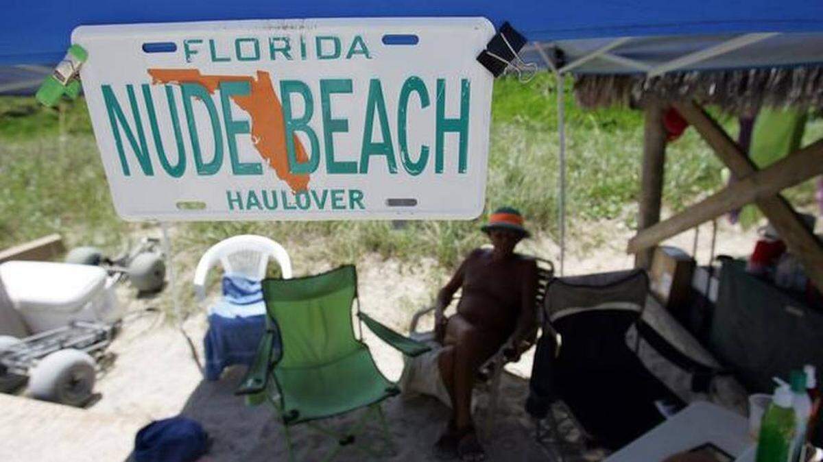 Un hombre sentado en su quiosco abierto a los nudistas en un tramo de Haulover Beach.